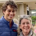 Young man in blue jacket smiling outside with older woman during Celebtime Tours 1 Day Home Away Tour, enjoying sightseeing.