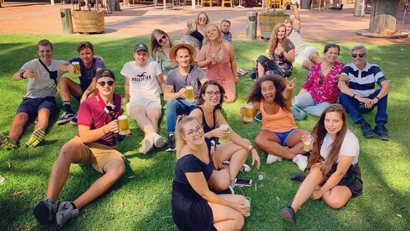 Guests relaxing with drinks on lush grass at a Full Day Swan Valley Wine Tour, bar and outdoor seating area featured in the background.