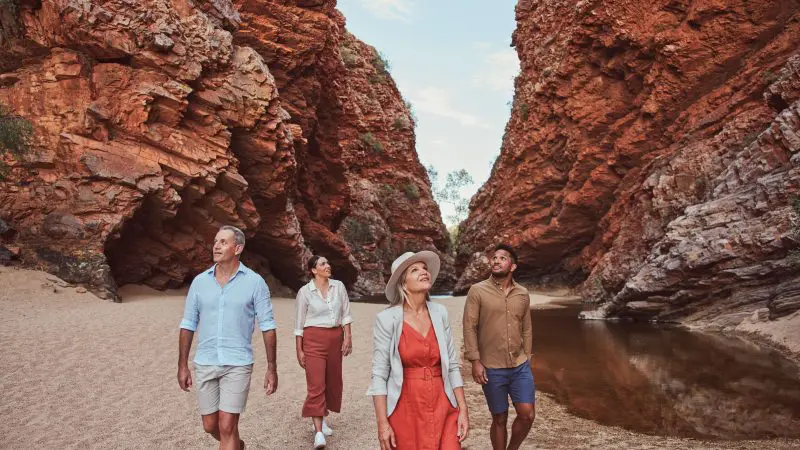 Four adventurers marvel at dramatic red cliffs and a crystal-clear pool on a 1 Day West MacDonnell Ranges tour with Standley Chasm.