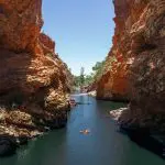 Experience a scenic river float between towering red canyon walls on a 4 Day Uluru to Alice Springs adventure tour in Australia.