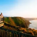 Family overlooks scenic ocean views from lush Phillip Island cliffs at sunset during Penguin Parade and Koala tour adventure.