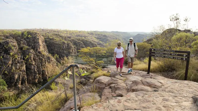 Adventurers traverse a rocky trail with sweeping canyon vistas on a 5-Day Kakadu, Katherine Gorge & Litchfield 4WD tour from Darwin.