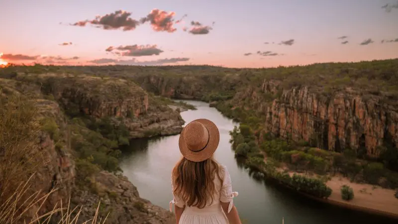A woman in a hat gazes over Katherine Gorge at sunset, ideal for a 1 Day Katherine Gorge Cruise and Edith Falls tour from Darwin.