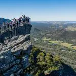 A group admires panoramic coastal views from a rocky lookout on the 3 Day Great Ocean Road Tour from Melbourne to Adelaide.