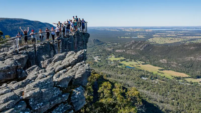 Travellers stand on a rocky lookout, admiring panoramic views along the 3 Day Great Ocean Road Grampians Explorer tour from Melbourne.