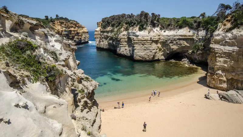 Pristine secluded sandy beach along the 3 Day Great Ocean Road from Adelaide to Melbourne, fringed by rugged cliffs and turquoise waters.