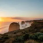 Breathtaking sunset illuminates limestone stacks and a scenic boardwalk at the Twelve Apostles on the Great Ocean Road, Adelaide to Melbourne.