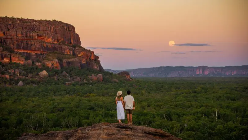 A couple admires a sunset view from a rocky cliff on a 3 Day Kakadu Litchfield National Park 4WD Safari Tour in Australia.