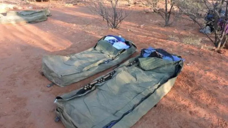 Two green camping swags with bedding on rich red earth, ideal accommodation for a 2 Day Uluru Kata Tjuta Rock Tour from Ayers Rock.