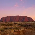 Breathtaking Uluru rock formation glowing at sunset, stunning outback vistas on 4 Day Uluru Kata Tjuta Kings Canyon tour Australia.