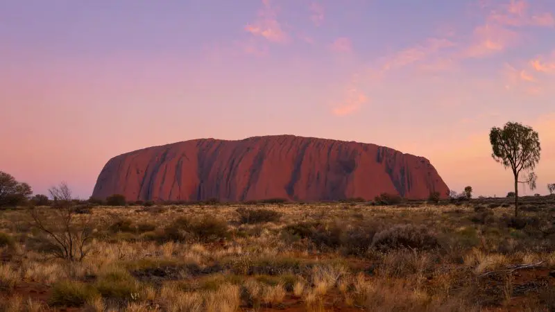 Breathtaking Uluru rock formation glowing at sunset, stunning outback vistas on 4 Day Uluru Kata Tjuta Kings Canyon tour Australia.