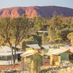 Luxury tented cabins blend seamlessly among lush trees, boasting iconic Uluru views—ideal for your 4 Day Uluru to Alice Springs tour.