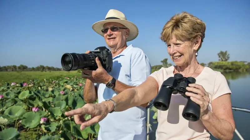 Happy senior couple enjoying birdwatching by lily pads on a Half Day Jumping Crocodile Tour from Darwin, Northern Territory.