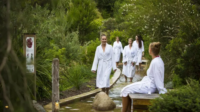Relaxing at Peninsula Hot Springs: five women in white robes enjoy a luxury footbath and spa entry via 1 Day Shuttle Bus.