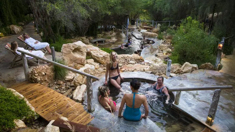 Visitors unwind in scenic outdoor Peninsula hot springs after convenient shuttle bus arrival with 1 Day Spa Entry, enjoying relaxation.