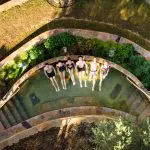 A group of six people in swimsuits unwind together at Peninsula Hot Springs, making the most of a 1 Day Spa Entry with Shuttle Bus.