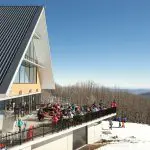 Group of skiers relaxing on a sunlit lodge terrace during a top-rated 1 Day Lake Mountain Snow Waterfalls Tour from Melbourne.