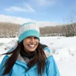 Happy woman in blue jacket and beanie enjoys scenic snowy landscape on Lake Mountain Snow Waterfalls Day Tour from Melbourne.