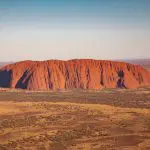Stunning aerial view of Uluru in Australia’s Red Centre, iconic landmark on the 7 Day Adelaide to Uluru Untamed Escapes adventure tour.