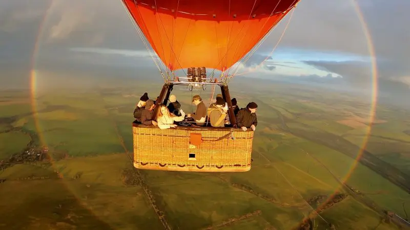 Experience an unforgettable Balloon Flight With Breakfast in Perth’s Avon Valley, floating over lush green fields with a rainbow below.