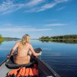 Woman paddling canoe on tranquil Noosa Everglades lake during 1 Day Explorer tour with Everglades Eco Safaris, scenic wilderness experience.