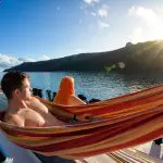 Couple relaxes in a hammock aboard Oz East Coast Adventure boat at sunset, enjoying tranquil water views on 28-day tour of Australia.