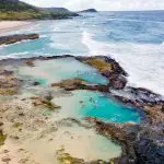 Stunning aerial view of crystal-clear natural rock pools beside the sea on a 28 Day Oz East Coast Adventure Intro Travel tour.