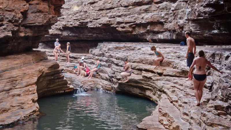 Travellers swim and unwind at a scenic canyon pool, featured in the Perth to Darwin Adventure Package with Broome accommodation.