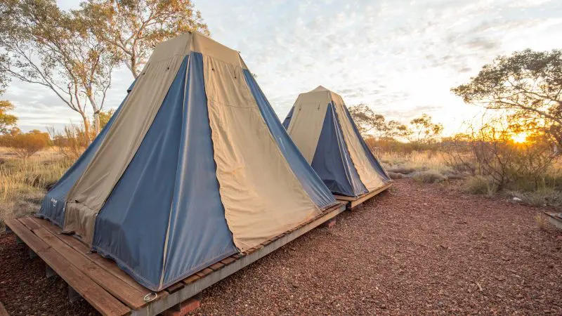 Sunrise view of two elevated canvas tents on lush grass, perfect for Perth to Darwin tours skipping Broome accommodation options.