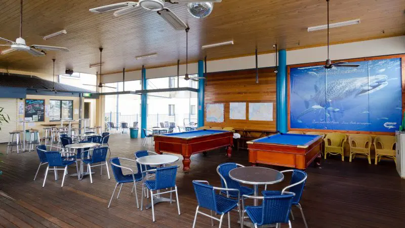 Spacious indoor lounge featuring blue chairs, pool tables, travel maps, and a vibrant whale shark mural—ideal for Broome to Perth tours.