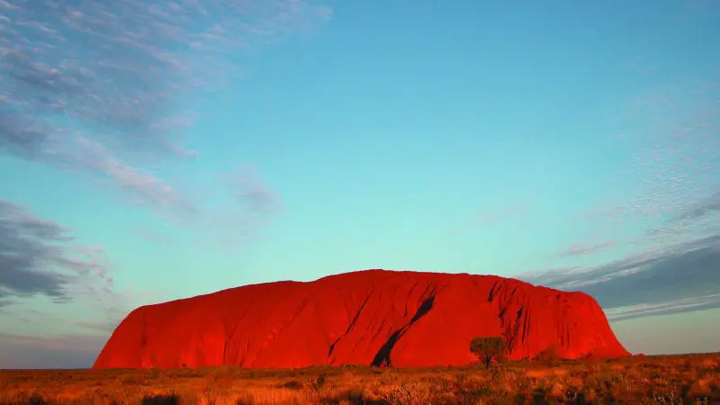 Experience the iconic Uluru, a striking red sandstone monolith beneath clear blue skies—ideal for your ultimate 2 Day 1 Night adventure.