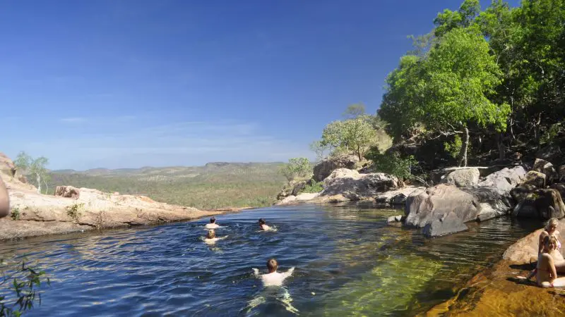 Visitors enjoying a pristine natural rock pool beneath a vibrant blue sky—top attraction on the Kakadu Tour Highlights 2 adventure.