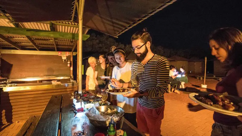Travellers savour a delicious outdoor buffet beneath a starry sky on the 3 Day Uluru Adventure from Alice Springs to Alice Springs.