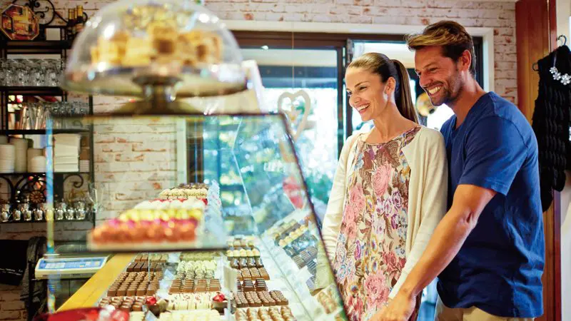 Happy couple browsing gourmet chocolates in a shop at O'Reilly's, Lamington National Park, on a Brisbane day trip.