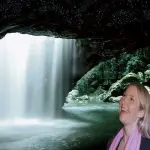 Smiling couple pose by a stunning cave waterfall during a popular Natural Bridge Glow Worm Night Tour from the Gold Coast, Australia.