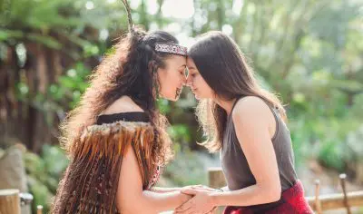 Two women hold hands and touch noses, sharing a heartfelt moment during their unforgettable Grand Kiwi Experience adventure.