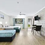 Spacious hotel room with double and single beds, flat-screen TV, work table, and large window—ideal stay before Kgari 2 Day Tour.