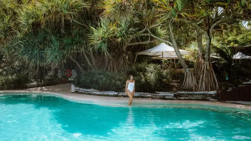 Woman in a white swimming costume relaxes poolside, surrounded by vibrant greenery during the luxurious Kgari 4 Day Experience getaway.