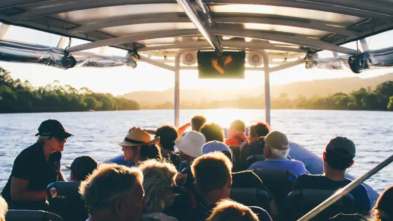 A group experiences a breathtaking sunset river cruise, admiring shimmering water and distant trees beneath a vibrant, cloudless sky.