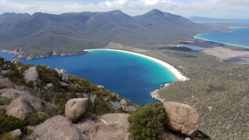 Scenic vista from a rocky outcrop overlooking a pristine curved white-sand beach on the 4 Day Wild Tasmania Wilderness Loop tour.