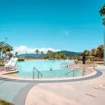 Expansive outdoor lagoon with crystal-clear water on the Ultimate East Coast Sydney to Cairns tour, scenic mountains in background.