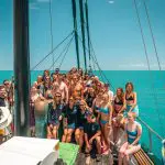 Group of friends in colourful swimwear enjoying a guided sailboat tour on the Ultimate East Coast Sydney to Cairns adventure.