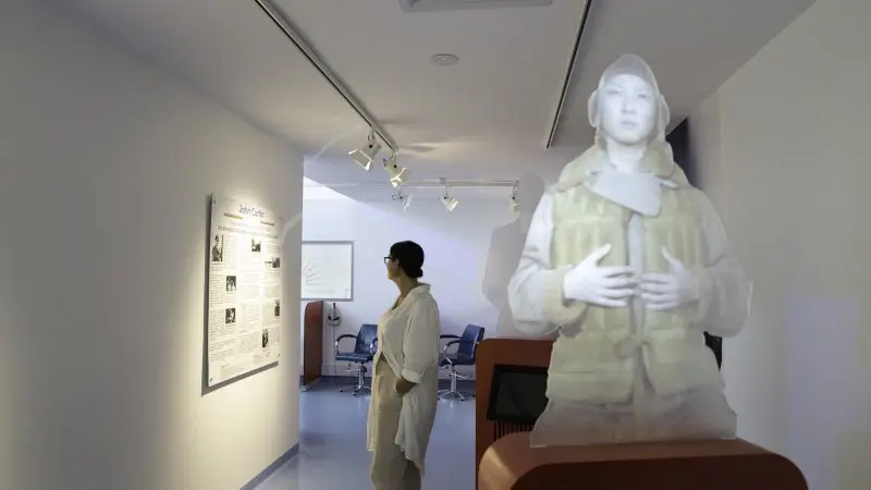 A visitor studies an information board next to a translucent figure at the RFDS Darwin Aviation Attraction Combo Ticket exhibit display.