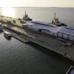 Stunning aerial view of Darwin dock with boats, RFDS Aviation Attraction Ticket building, and vibrant sunset reflecting on the waterfront.