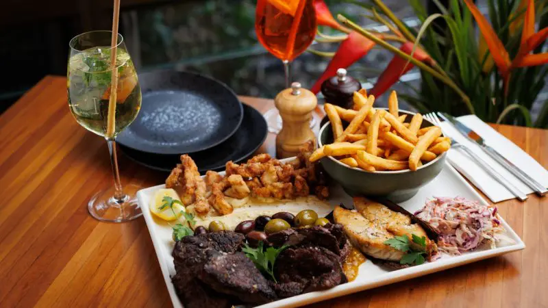Indulgent platter of grilled meats, crispy chips, and vibrant cocktails captures the authentic tastes of a 2 Day Kakadu Outback Retreat.