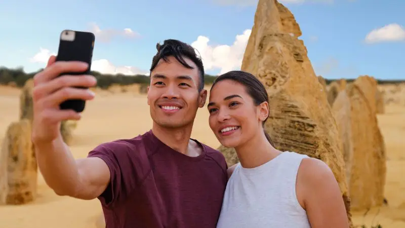 Smiling couple pose for a selfie in Western Australia’s Pinnacles desert during a top-rated Perth day tour with lobster and lavender stops.