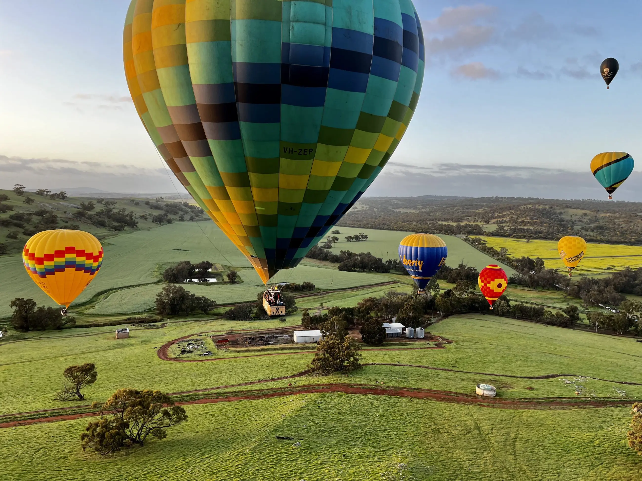 Vibrant hot air balloons soar over Avon Valley’s scenic fields at sunrise during the popular Balloon Flight With Breakfast Perth experience.