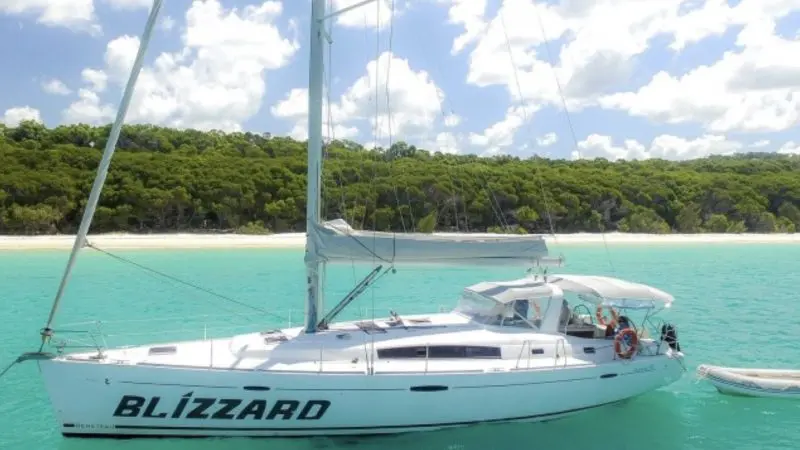 A sleek white sailboat, BLIZZARD, glides on vibrant turquoise Whitsunday waters—ideal for a 3-day, 2-night sailing adventure.
