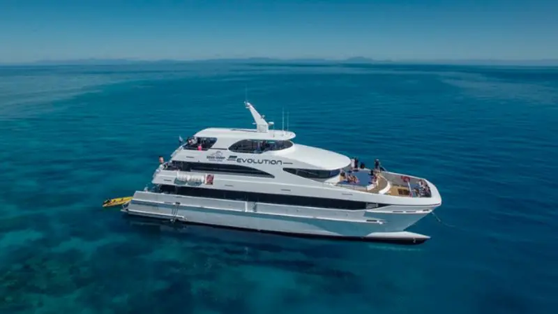 Experience the Full Day Great Barrier Reef Cruise aboard the Evolution yacht, gliding on crystal-clear ocean under a radiant blue sky.