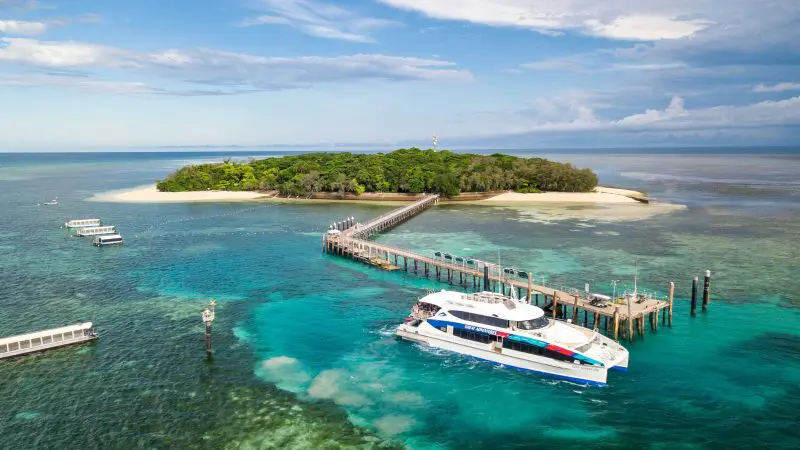 White boat at Green Island pier over crystal-clear turquoise water, ideal for snorkelling or glass-bottom boat tours in Australia.